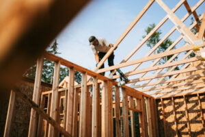 Workers build the frame of a new house project. Bare plywood and beams as it is framed up from the foundation. High lumber costs have affected the building process. Shot in Washington state, USA.